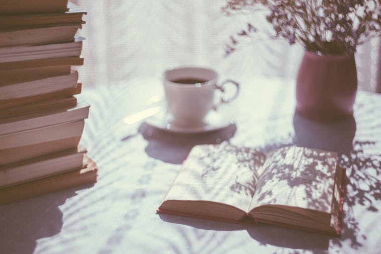 A serene scene featuring books, a coffee cup, and shadows creating a cozy ambiance.